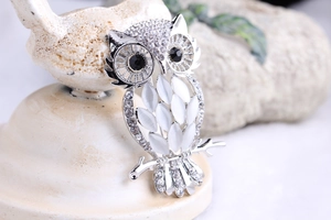 Macro shot of owl brooch with white opal stones and sparkling diamond accents