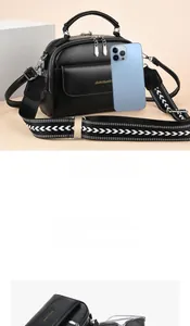 Dettaglio della grande borsa a tracolla nera con tracolla geometrica e cellulare