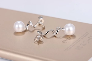 Close-up of spiral silver earrings with white pearls and sparkling cubic zirconia stones