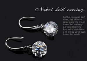 Macro view of 8mm round cut naked diamond earrings with silver hook settings on black background