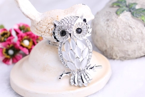 Close-up of owl brooch with white cat eye stone and sparkling diamonds on a branch