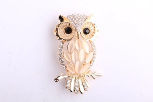 Close-up of golden owl brooch with opal stones, rhinestones and black gem eyes