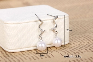 Detailed view of silver spiral earrings with zircon crystals and 8mm round pearls