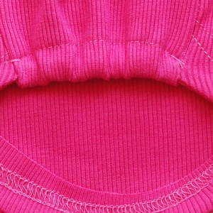Close-up of rose red ribbed knit fabric showing detailed stitching and premium texture