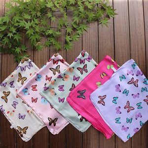 Detailed overhead view of five colorful butterfly pattern silk scarves on wood