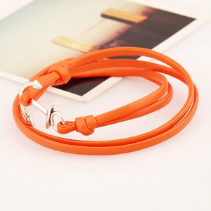 Macro detail of orange multi-layer leather bracelet with silver anchor buckle