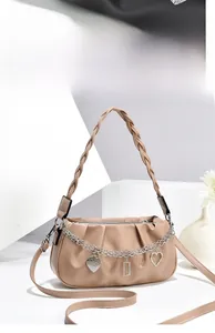 Detail of beige cloud-shaped handbag with woven handle and decorative silver chains