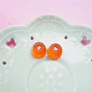 Macro detail of orange resin heart charms with spiral texture for DIY jewelry crafts