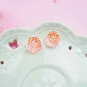 Macro shot of two translucent orange-pink shell-shaped resin charms in a ceramic dish