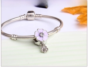 Detail of silver snake chain bracelet with purple enamel clover and flower charms