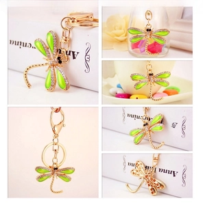 Detail view of a golden dragonfly keychain with green enamel wings and white rhinestones