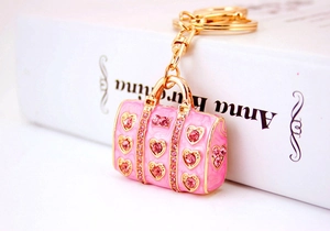Detail of pink enamel handbag keychain with heart rhinestone on white book edge