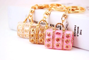Detailed view of three enamel rhinestone handbag keychains in pink, beige and white colors