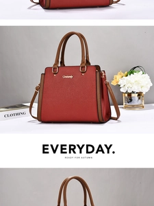 Detail shot of the red lychee textured handbag with brown leather handles and gold logo