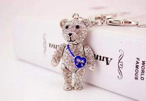 Macro view of crystal teddy bear keychain with blue heart bag and silver metallic bow