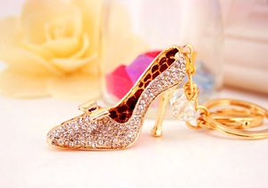 Détail d'un porte-clés escarpin doré orné de strass brillants et d'une perle décorative