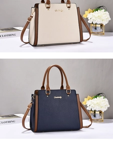 Detail view of lychee pattern leather tote bags in cream and navy blue with gold logos