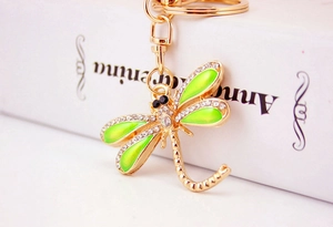 Close-up of a green dragonfly keychain with gold plating and sparkling rhinestones