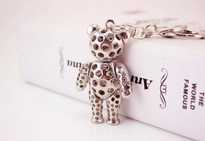 Macro shot of a hollow metal bear keychain resting on a book with soft pink lighting