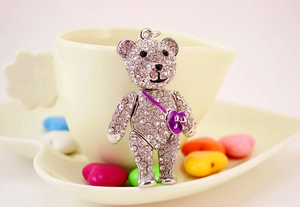 Macro shot of silver metal bear pendant with crystals and purple heart on heart-shaped dish