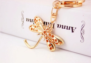 Detailed close-up of golden dragonfly keychain with intricate floral cutout patterns