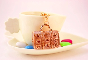 Macro view of rose gold handbag keychain with crystal inlay and heart enamel patterns