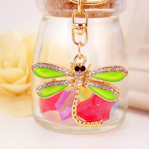 Golden dragonfly keychain with green enamel wings and crystal rhinestones on a bag charm