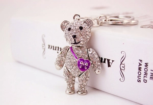 Close-up of sparkling rhinestone bear keychain with purple heart charm and silver metal finish