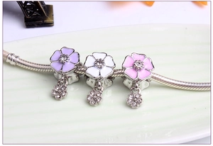 Detailed view of purple, white, and pink enamel flower pendants with sparkling crystal inlay