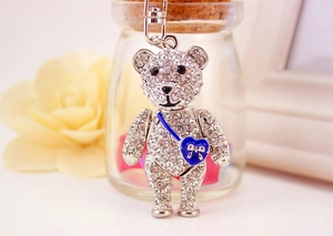 Macro shot of a silver teddy bear keychain with clear crystals and a blue heart bag
