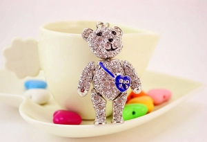 Detail of silver bear keychain with clear rhinestones and blue heart-shaped crossbody bag
