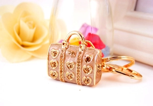 Close-up of beige handbag keychain with gold heart details and amber rhinestones