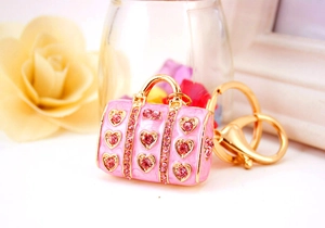 Close-up of pink enamel handbag keychain with sparkling heart-shaped rhinestones and gold hardware