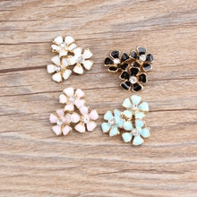 Detail of colorful enamel flower charms with rhinestones on a rustic wooden background