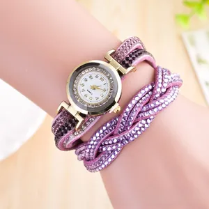 Close-up of a women's purple rhinestone wrap bracelet watch worn on a wrist over wood