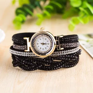 Macro detail of multi-layer wrap watch with black rhinestone straps and a gold quartz dial
