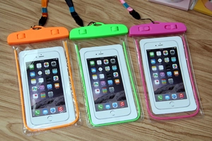 Close-up of triple waterproof phone pouches in orange green and pink on wood