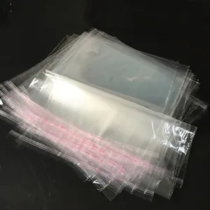 Stacks of transparent self-sealing OPP plastic bags with pink adhesive strips for packaging
