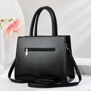 Close-up of golden metal zipper and smooth stone pattern texture on the black handbag