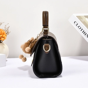 Vue détaillée du côté du sac bicolore avec boucles dorées et pendentif en peluche