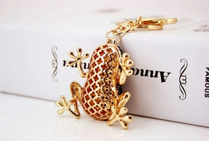 Close-up of golden metal frog keychain with hollow back design on a book edge