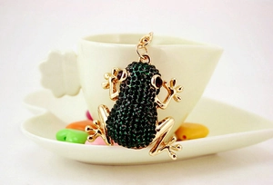 Close-up of golden frog keychain with dark green rhinestones and red gem eyes