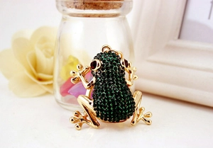 Macro detail of a golden frog keychain encrusted with green and red sparkling crystals