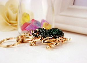 Macro detail of golden frog keychain with sparkling green and red rhinestones