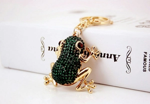 Detailed view of frog keychain with green rhinestones and gold metal finish