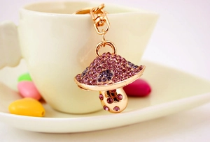 Dettaglio ravvicinato del portachiavi a fungo dorato con strass viola e rosa