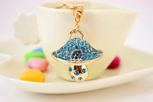 Primo piano portachiavi a fungo dorato con strass blu accanto a una tazza bianca
