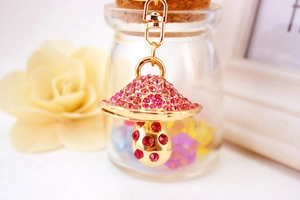 Close-up of a mushroom keychain with sparkling pink and red rhinestones on gold alloy