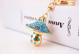 Close-up of golden mushroom keychain with sparkling blue rhinestones on a book background