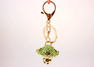 Close-up of a green rhinestone mushroom keychain with a gold metal clasp and chain